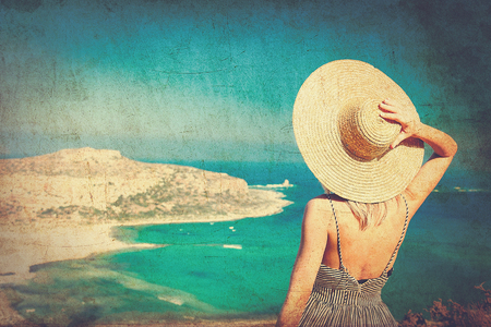 Young redhead girl in hat and dress with sea coastline on Balos, Crete, Greece . Image in retro styleの写真素材