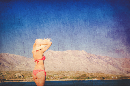 Young redhead girl in hat and bikini on Elafonissi beach, west Crete, Greece. Summertime season. Image in retro styleの写真素材