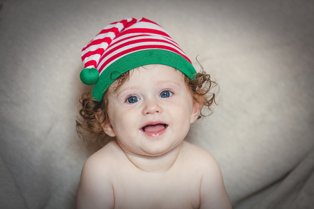 Little smily baby boy in elf hat on grey background. Christmas season imageの写真素材
