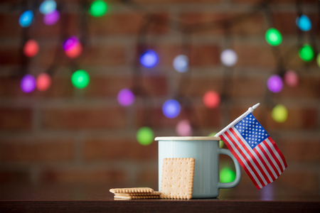 Hot cup of coffee, US flag and cookie with fairy lights on background. Christmas seasonの写真素材
