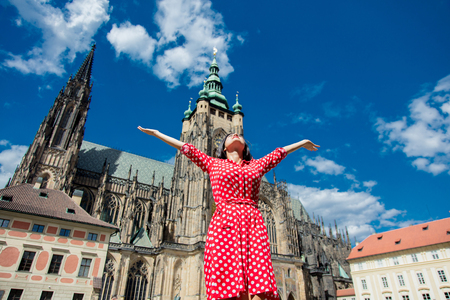 Beautiful girl in red dress travel in Prague, Church on backgroundの写真素材