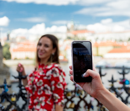 Beautiful brunette girl in red dress make a photo in Prague, city streetsの写真素材