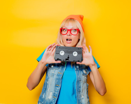 portrait of young adult girl orange hat with VHS on yellow backgroundの写真素材