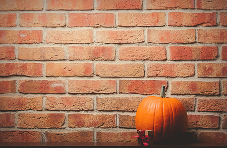 one orange pumpking and gift box on brick wall background. Image with side cornet lightの写真素材