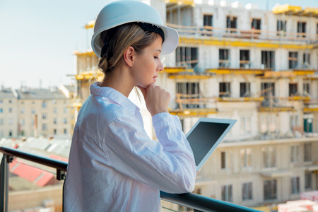 Young engineer woman with helmet and tablet on building.の写真素材