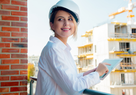 Young engineer woman with helmet and tablet on building.の写真素材