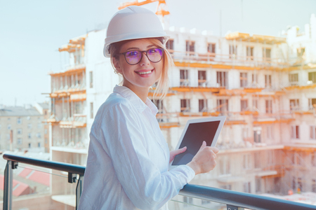 Young engineer woman with helmet and tablet on building.の写真素材
