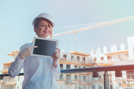 Young engineer woman with helmet and tablet on building.の写真素材