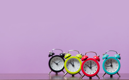 Group of color alarm clocks on purple background