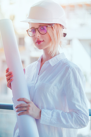 Young engineer woman with helmet and plan on building.の写真素材