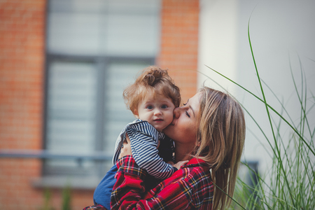 Young mother with a baby boy at outdoor near urban house in the city.の写真素材