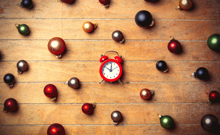 Alarm clock with Christmas baubles around on wooden table. Above view in old color styleの写真素材