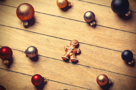 gingerbread man with Christmas baubles around on wooden table. Above view in old color styleの写真素材