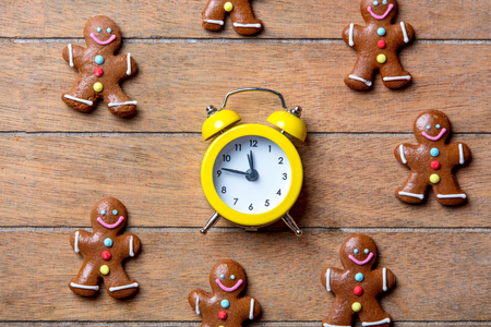 Christmas gingerbread man and alarm clock on wooden table. Above view in old color styleの写真素材
