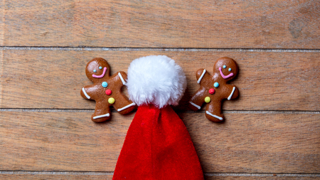 Gingerbread cookie and Santa Claus hat on wooden table