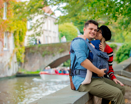 Young family, dad, mother and a child sitting at bridge in Bruges, Belgiumの写真素材