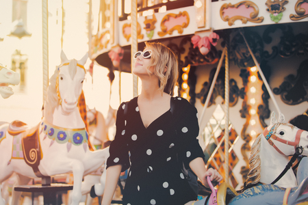Young style girl in sunglasses and black dress stay in merry go round carousel in Strasbourg, Franceの写真素材