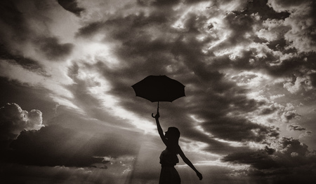 Photo of young beautiful woman with red umbrella on the sky background. Image in black and white color styleの写真素材