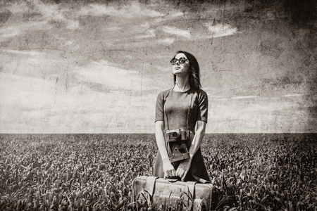 portrait of young beautiful woman with suitcase in the field. Image in black and white color style