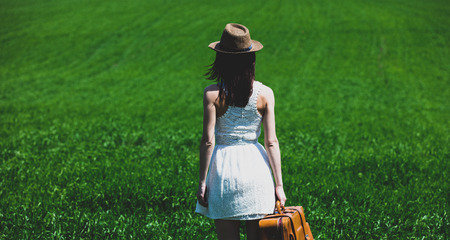 Photo of young beautiful woman with suitcase in the fieldの写真素材