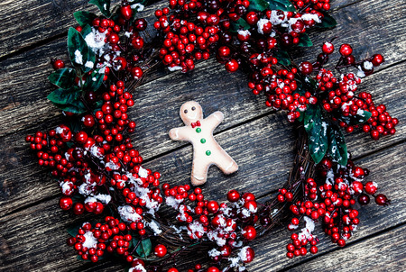Holly christmas wreath with gingerbread man on wooden table.の写真素材