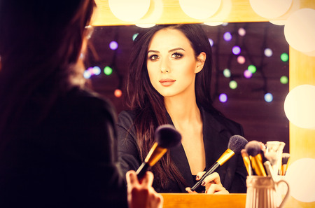 portrait of young beautiful woman with brush looking in the mirror