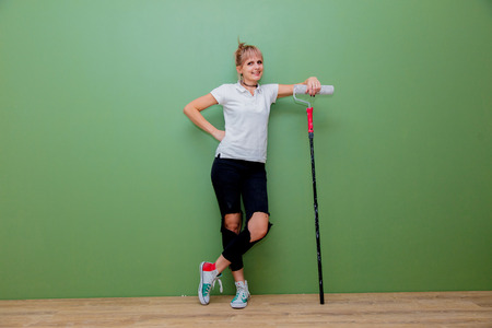 Young woman with paint roller in own house after painting a room. Real people