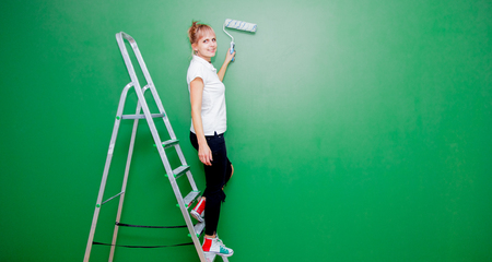 Young woman with paint roller and ladder in own house after painting a room. Real peopleの写真素材