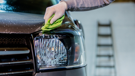 Man's hand washing a car headlight on car washの写真素材