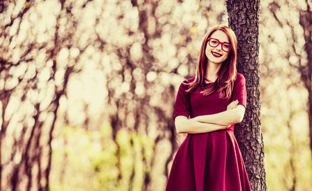 Young woman with in red classic dress stay near tree in a park in spring time season.の写真素材