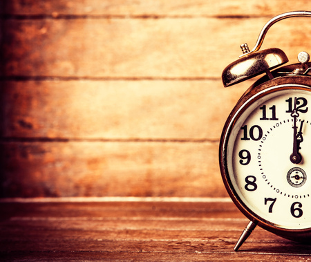 Gray metal alarm clock on a wooden table and background