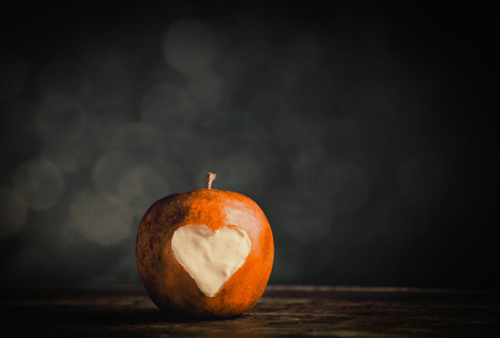 Apple with a heart shape cut into it. Photo in old color image style.の写真素材