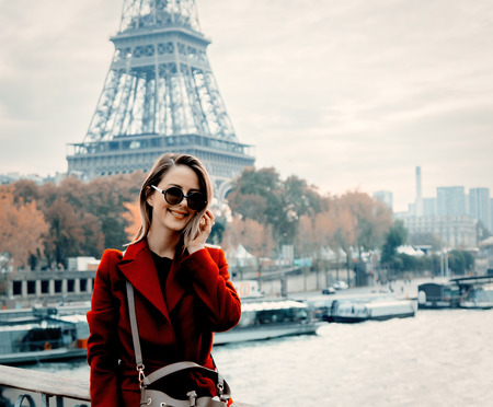 Style redhead girl in red coat make a photo on parisian street in autumn season time. Eiffel tower on backgroundの写真素材