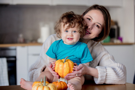 Happy white mother and son with pumpkin. Domestic image at kitchenの写真素材