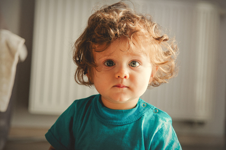 Portrait of a little toddler boy with curlly hair looking at camera. indoorの写真素材