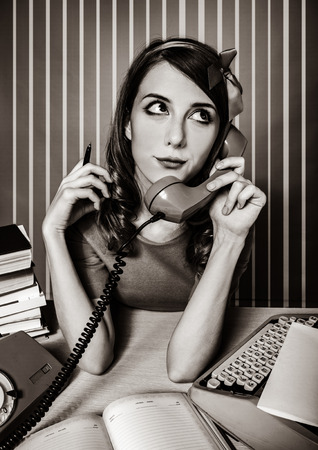 young woman as secretary at her desk near the typewriter and dial phone. 60-s style. Image in black and white color styleの写真素材