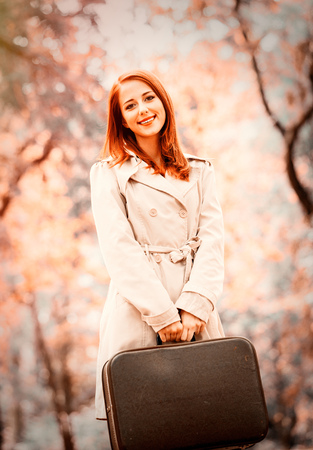 Style redhead girl with suitcase on autumn season park. Image with filterの写真素材