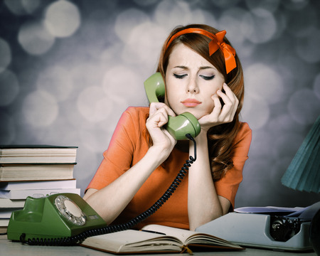 young woman as secretary at her desk near the typewriter and dial phone. 60-s style.の写真素材