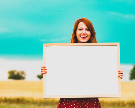 young farm girl holding white board in her hands against the background of the field. Farmの写真素材