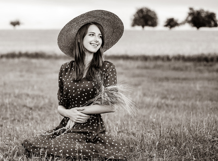 young girl from farm in a hat holding wheat ears in her hands against the background of the field. Farm. Image in black and white color styleの写真素材