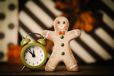 Gingerbread man and alarm clock with gifts on background