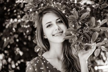 Beautiful smiling girl stay near apple tree and looking in to the camera. Image in black and white color styleの写真素材