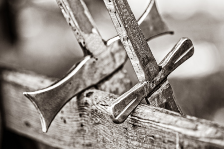 Two metal swords on wooden desk. Image in black and white color styleの写真素材