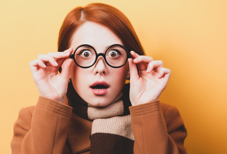 Redhead girl scarf and coat on yellow background.の写真素材
