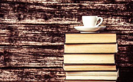 stack of books and cup of coffee on wooden background.の写真素材