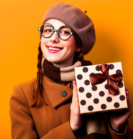 Redhead girl with gift box on yellow background.の写真素材