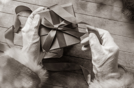 Santa Claus have wrapping a Christmas box on wooden background . Image in black and white color styleの写真素材