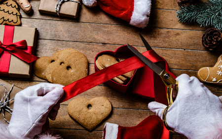 Santa Claus have wrapping a Christmas cookie and other gifts on wooden backgroundの写真素材