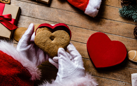 Santa Claus have wrapping a Christmas cookie and other gifts on wooden background