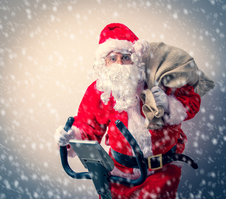 Funny Santa Claus have a fun with Exercise Bikes on white backgroundの写真素材